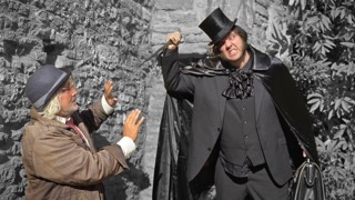 The Ripper raising a knife over Dr Martin against a stone wall