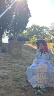 Eileen Daly in costume, seated among the gravestones
