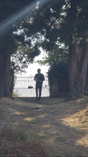 The priest silhouetted at the churchyard gate
