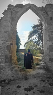 The Ripper standing in a ruined gothic arch, knife in hand