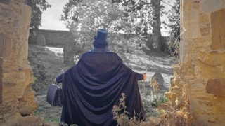 The Ripper from behind, cloaked, walking into the ruins